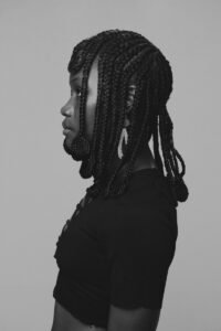 A striking black and white profile portrait of a woman with intricately braided hair in Ghana.