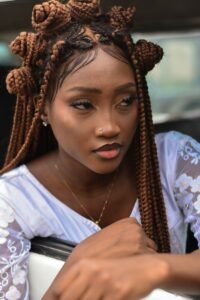 Stylish portrait of a young woman with braided hair and elegant attire.