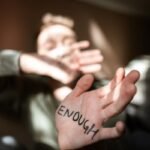 Blurred person with 'Enough' written on palm, expressing empowerment and resilience.
