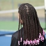 a woman with long box braids on a tennis court
