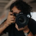 man in black shirt holding black dslr camera