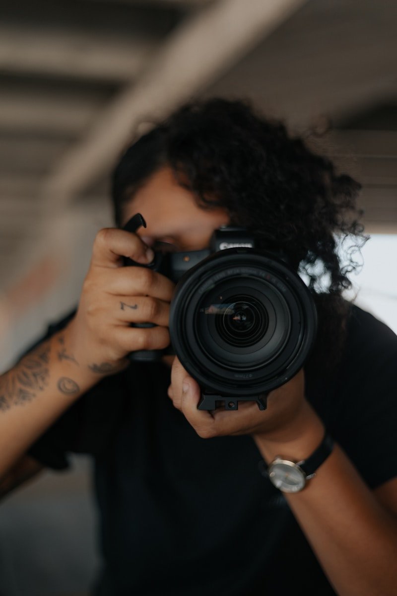 man in black shirt holding black dslr camera